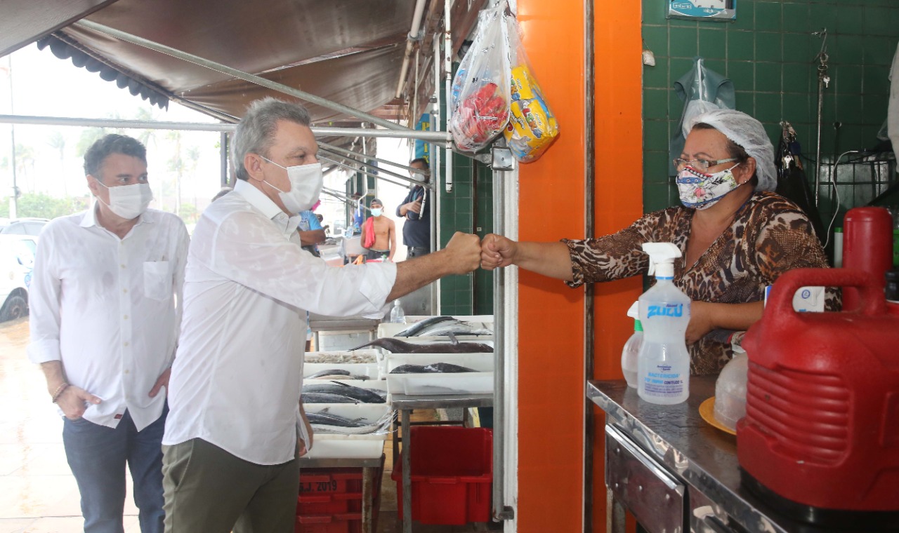 prefeito sarto cumprimenta, à distãncia, uma feirante do mercado dos peixes. ambos usam máscara